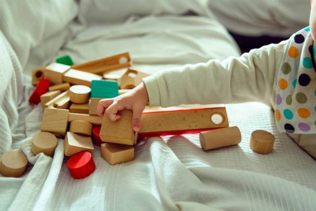 El bebé se divierte eligiendo cubos de madera para jugar con ellos y desarrollar su sentido de la orientación espacial.