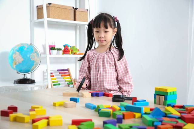 Child in front of scattered wooden blocks that will teach her counting skills