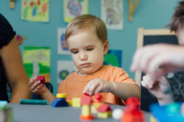 Focused toddler playing with blocks and learning shapes