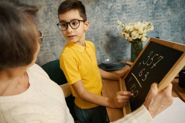 Une femme aide son petit-fils à réviser ses maths à la maison