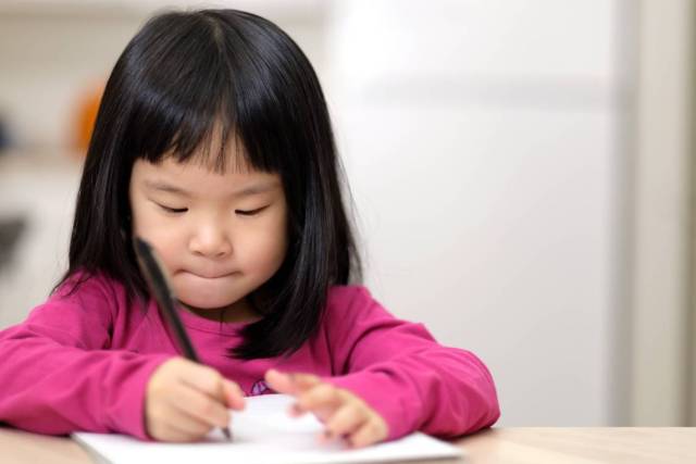 Young girl with dysgraphia writing on paper