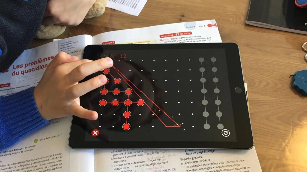 Child completing a visual-spatial grid activity on a tablet using Magrid
