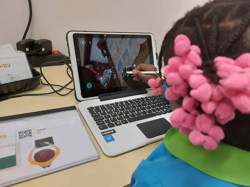 Un enfant utilise un stylet pour participer aux activités de développement cognitif visuel de Magrid sur l'écran d'un ordinateur portable, chez lui