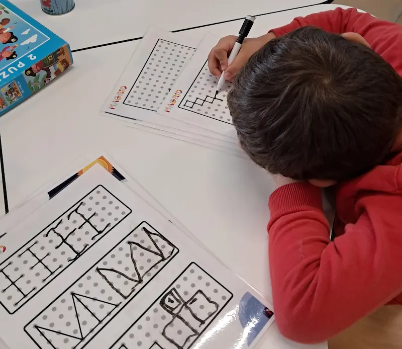 Enfant atteint de dyspraxie réalisant une activité de dessin de motifs visuels « Magrid » à l'aide de fiches d'activité imprimées