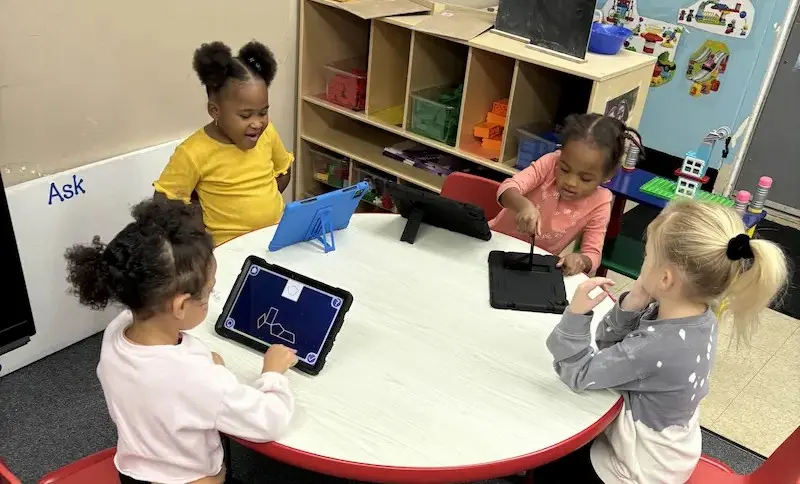 Young children using Magrid's visual cognitive development method independently on tablets at a small group table